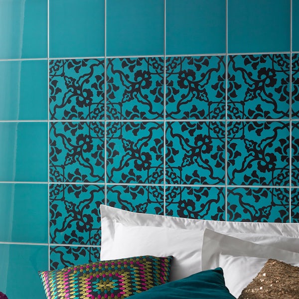 bed pillows in front of a tiled turquoise wall with black pattern